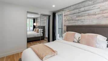 Un dormitorio moderno con una cama grande, una pared de acento de madera y un espejo que refleja la habitación.