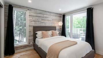 Une chambre moderne avec un grand lit, un plancher en bois et de grandes fenêtres avec des rideaux.