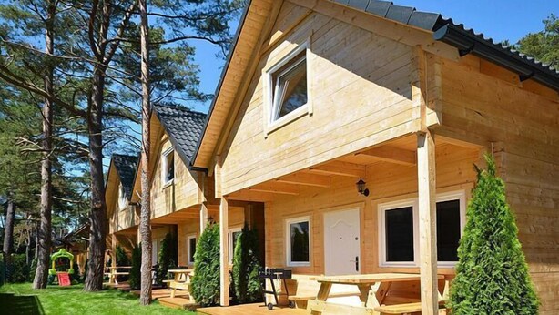 A wooden cabin with a covered porch, a dining area, and a small garden. - Chalet in Pobierowo near Baltic Sea Beach (Pobierowo)
