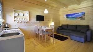 A wooden interior with a dining area, a sofa, a TV, and a painting on the wall. - Chalet in Pobierowo near Baltic Sea Beach (Pobierowo)