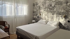 Un dormitorio con cama, una silla, una mesa y un mural en la pared de un bosque tropical.