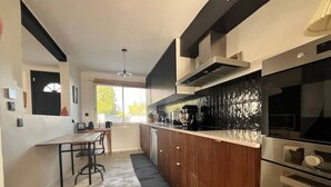 Una cocina moderna con una isla central, electrodomésticos de acero inoxidable y un salpicadero negro.