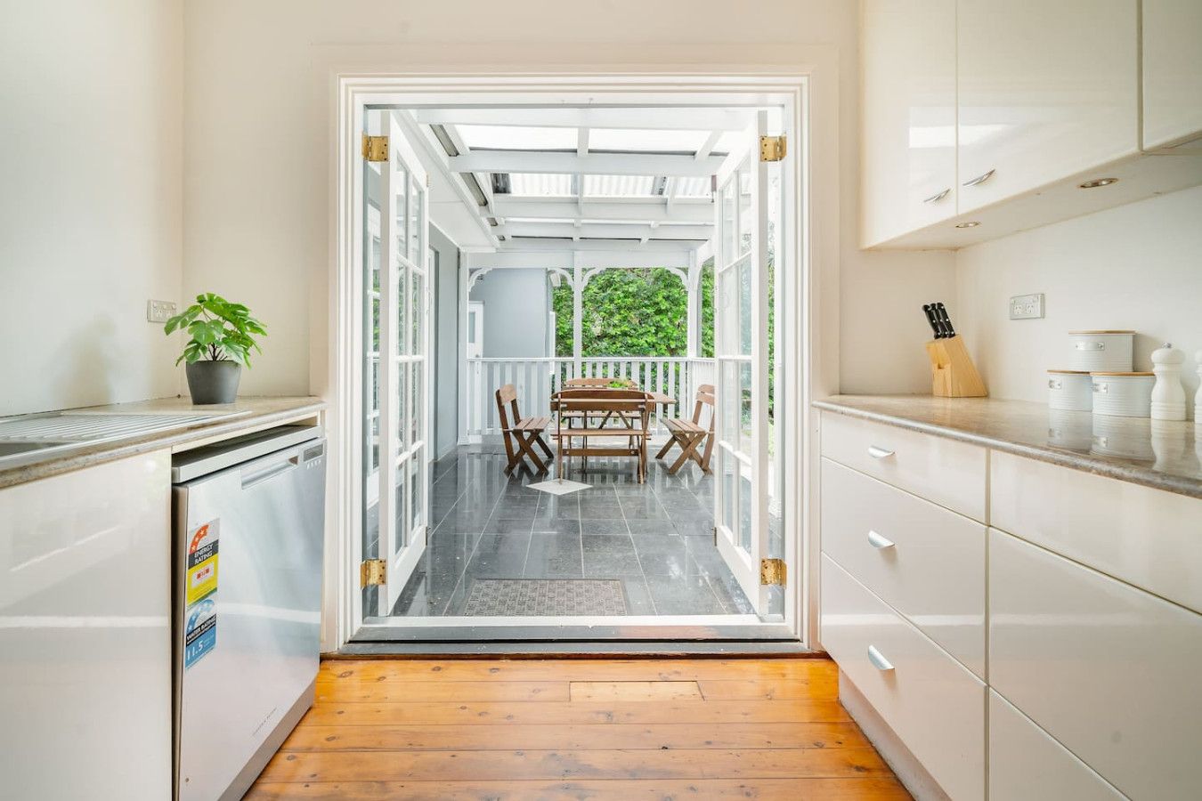 A kitchen with white cabinets, a wooden floor, and a dining area with a table and chairs.