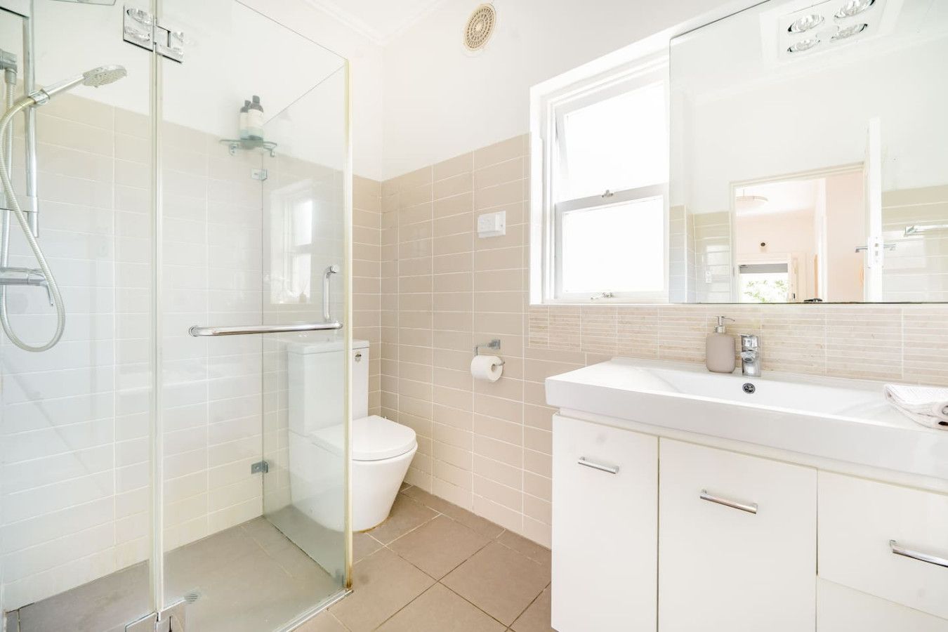 A modern bathroom with a glass shower enclosure, a toilet, and a vanity with a mirror.
