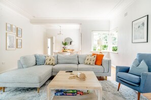 A modern living room with a grey sectional sofa, a blue armchair, and a coffee table with board games.