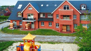 Un edificio de ladrillo rojo con un parque infantil al frente.