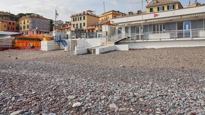 A coastal building with a white facade, a red cross symbol, and a staircase leading to a balcony. - L'Aria del Mare by Wonderful Italy (Genoa)