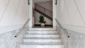 A marble staircase with a handrail, leading to a landing with a potted plant. - L'Aria del Mare by Wonderful Italy (Genoa)