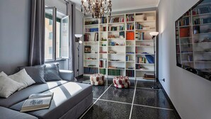 A modern living room with a grey sofa, a large bookshelf, and a chandelier. - L'Aria del Mare by Wonderful Italy (Genoa)