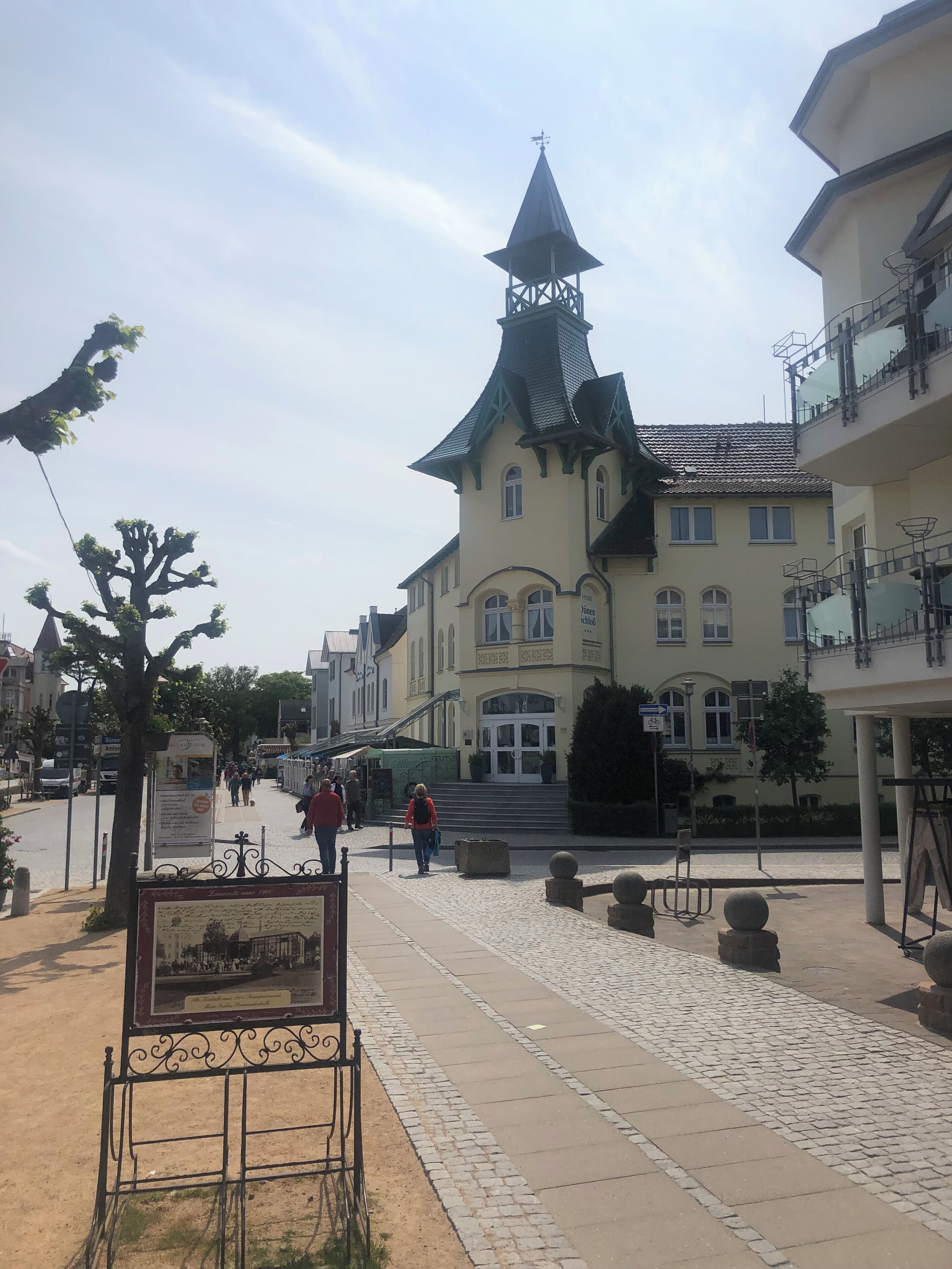 A historic building with a prominent tower and a signboard in front.