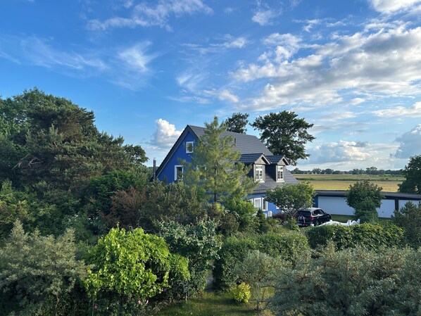 A blue house with a sloped roof surrounded by dense greenery and trees. - Ruhe & Meer (Trassenheide)