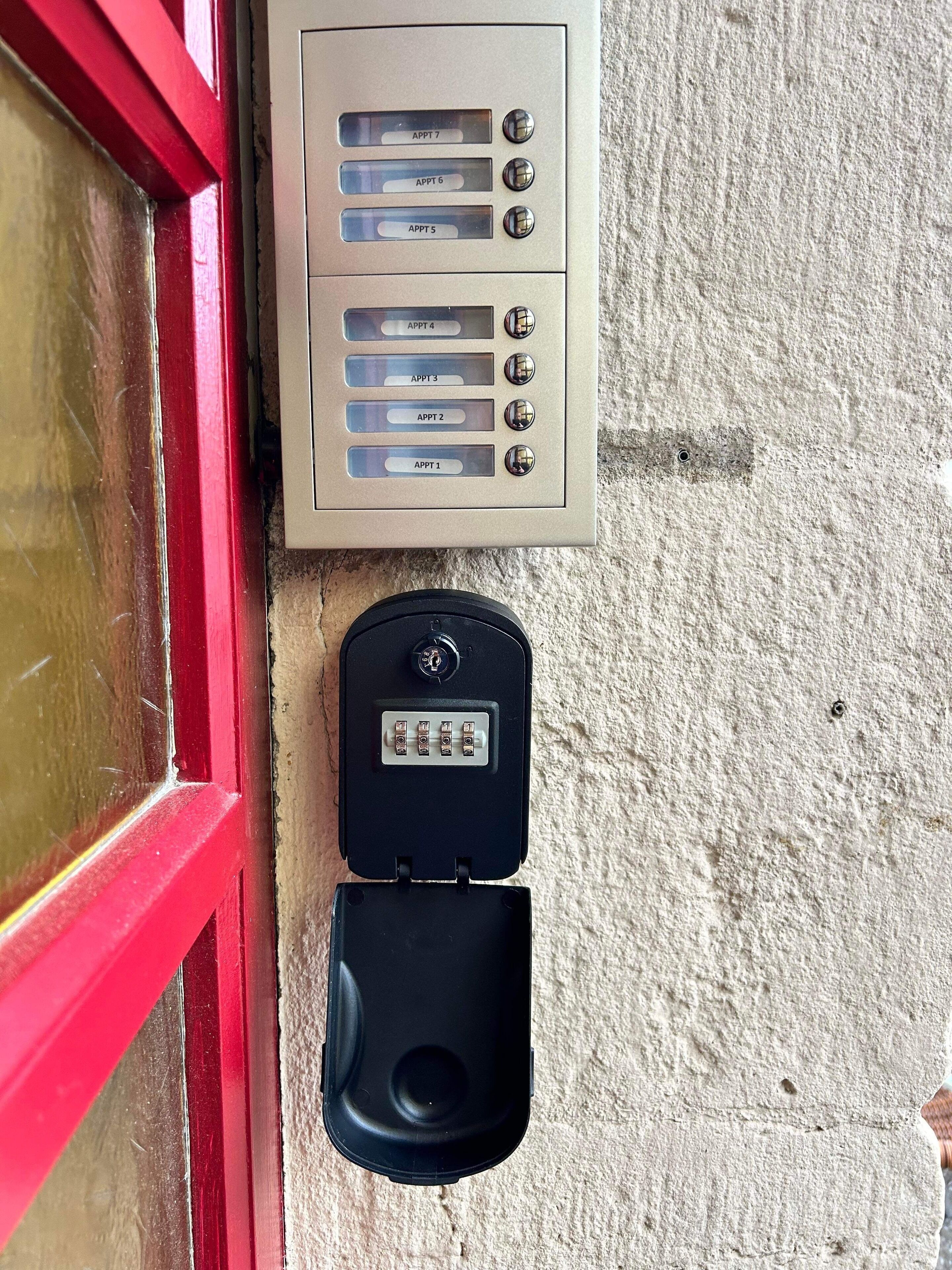 A wall-mounted intercom system with numbered buttons labeled APPT 1 through APPT 7, and a separate doorbell button below it.