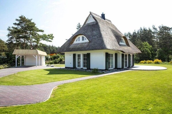 A house with a thatched roof, white walls, and a well-maintained lawn.
