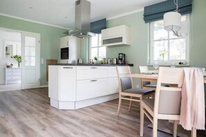 A modern kitchen with white cabinetry, a central island, and a dining area with a table and chairs.