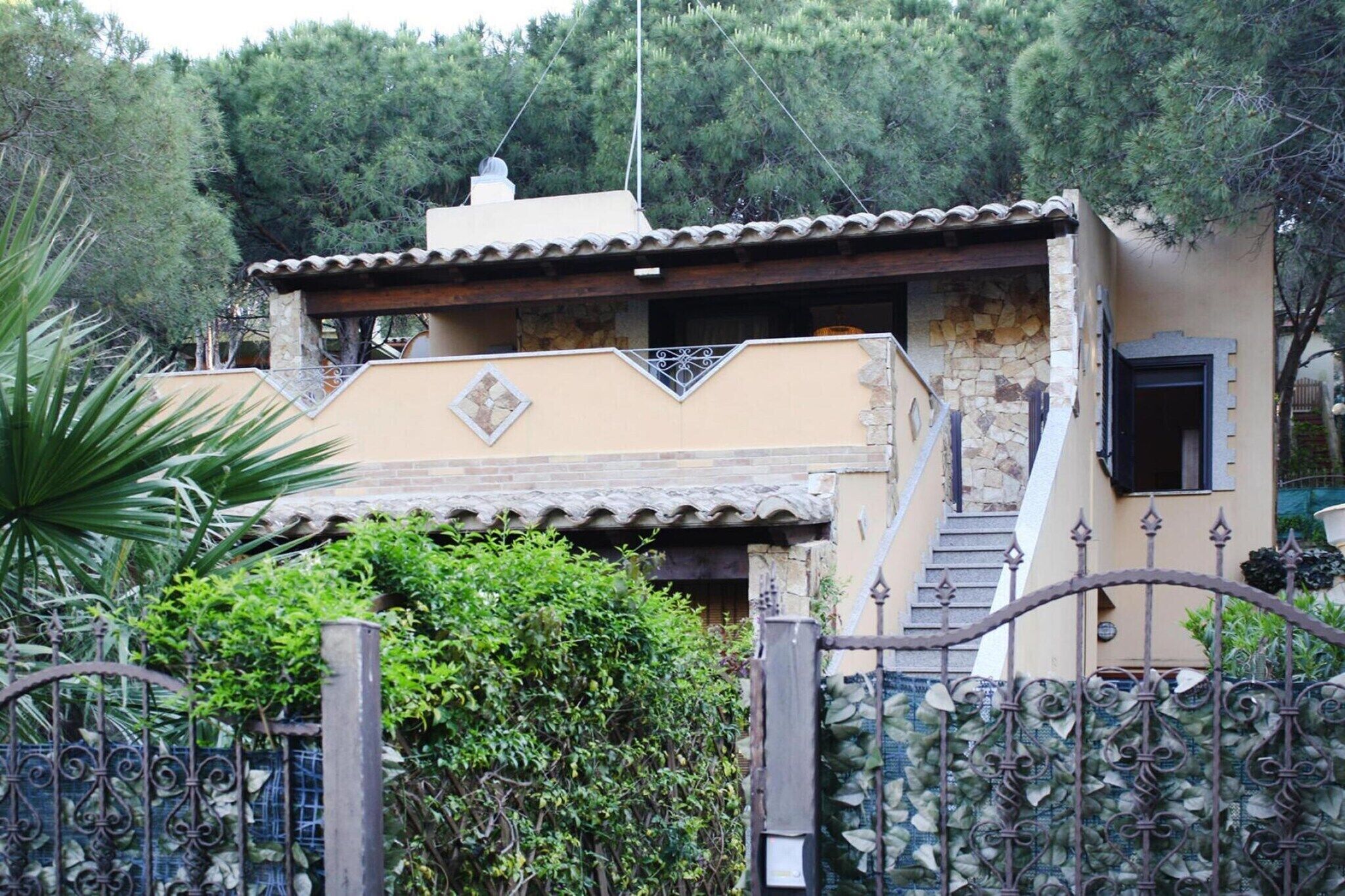 A two-story building with a tiled roof, a stone staircase, and a metal gate.