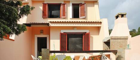 A two-story house with a balcony, a door, and a window with shutters.