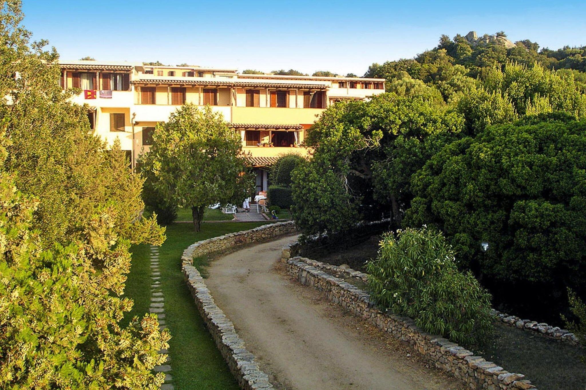 Un edificio con un patio interior, rodeado de árboles y un muro de piedra.