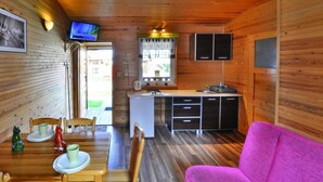 A compact cabin with a dining area, kitchenette, and a pink sofa.