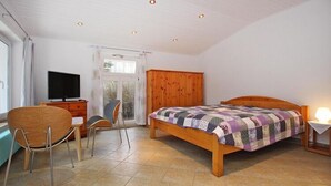 Een slaapkamer met een houten bed, een televisie, een bureau en een stoel.