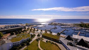 A marina with boats docked, a pier extending into the water, and buildings with green roofs. - Ferienhaus in Damp mit Meeresstrand (Damp)