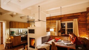 A cozy cabin interior with a dining area, kitchen, and fireplace. - Doppelhaushälften, Torfhaus (Torfhaus)