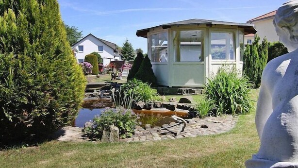 A garden with a pond, a gazebo, and a statue. - Ferienhäuser am Teich, Zinnowitz (Zinnowitz)