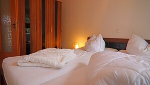 A hotel room with a bed, a wardrobe, and a nightstand with a lamp. - Ferienhäuser am Teich, Zinnowitz (Zinnowitz)