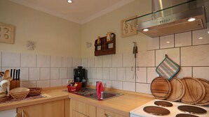 A kitchen with wooden cabinets, a stove, and a sink. - Ferienhäuser am Teich, Zinnowitz (Zinnowitz)
