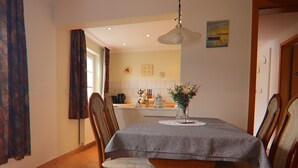 A dining area with a table set for four, wooden chairs, a vase with flowers, and a painting on the wall. - Ferienhäuser am Teich, Zinnowitz (Zinnowitz)