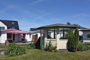 A residential area with a gazebo, a patio with a red umbrella, and a well-maintained lawn. - Ferienhäuser am Teich, Zinnowitz (Zinnowitz)