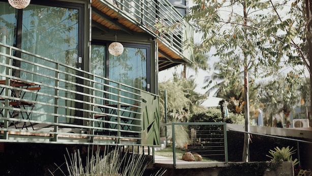 Un bâtiment moderne doté d’un balcon, d’un espace extérieur aménagé pour s’asseoir et d’un jardin bien entretenu.