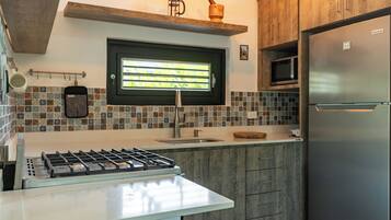Una cocina moderna con estufa a gas, refrigerador de acero inoxidable y una ventana con persianas.