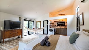 Une chambre d’hôtel moderne dotée d’un grand lit, d’une télévision, d’un hamac et d’une kitchenette.
