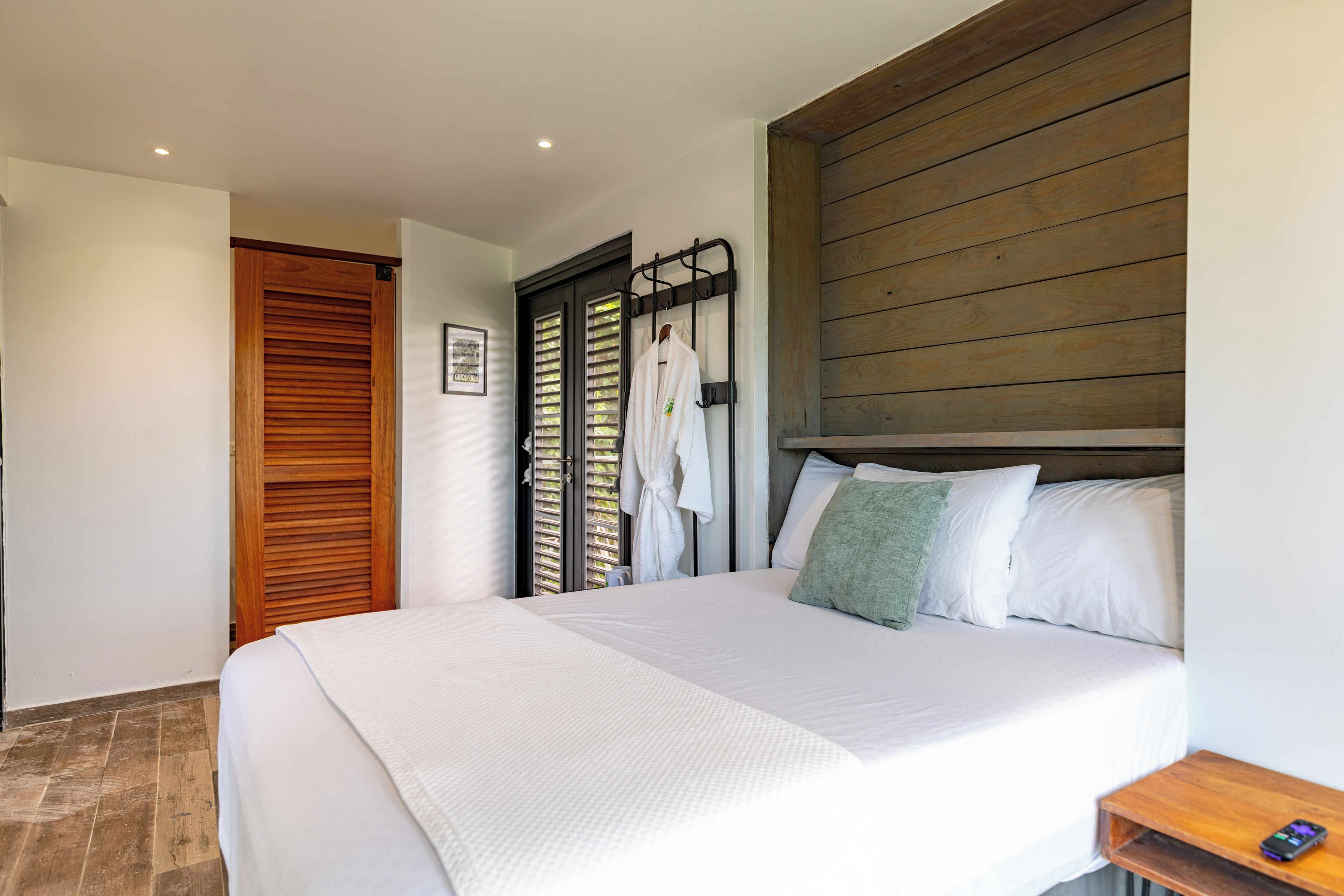 A hotel room with a large bed, wooden headboard, and a wooden door.