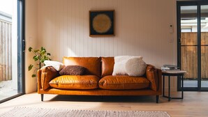Un salon moderne avec un canapé en cuir, une petite table d’appoint et une œuvre d’art encadrée accrochée au mur.