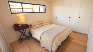 Une chambre à coucher avec un lit, une table de chevet avec une lampe, une fenêtre et une armoire.