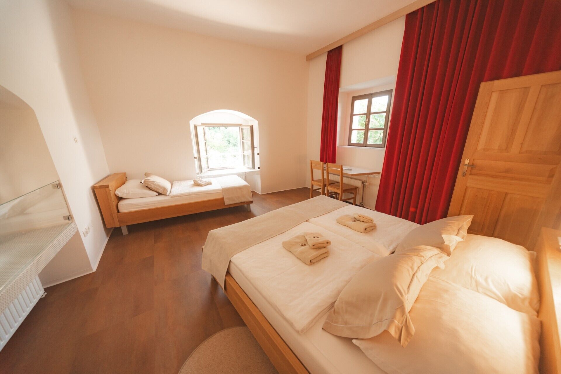 Een slaapkamer met twee bedden, een bureau, een raam en een radiator.
