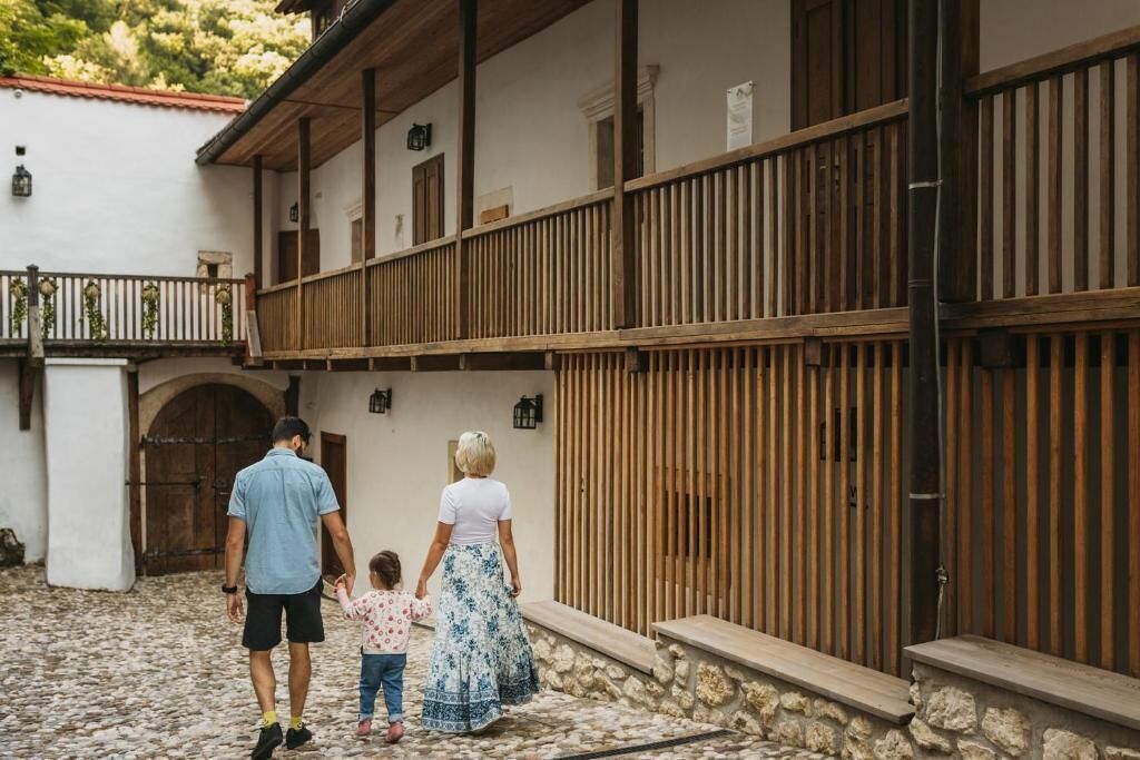 A courtyard with a stone floor, wooden balcony railings, and a white building with a red-tiled roof.