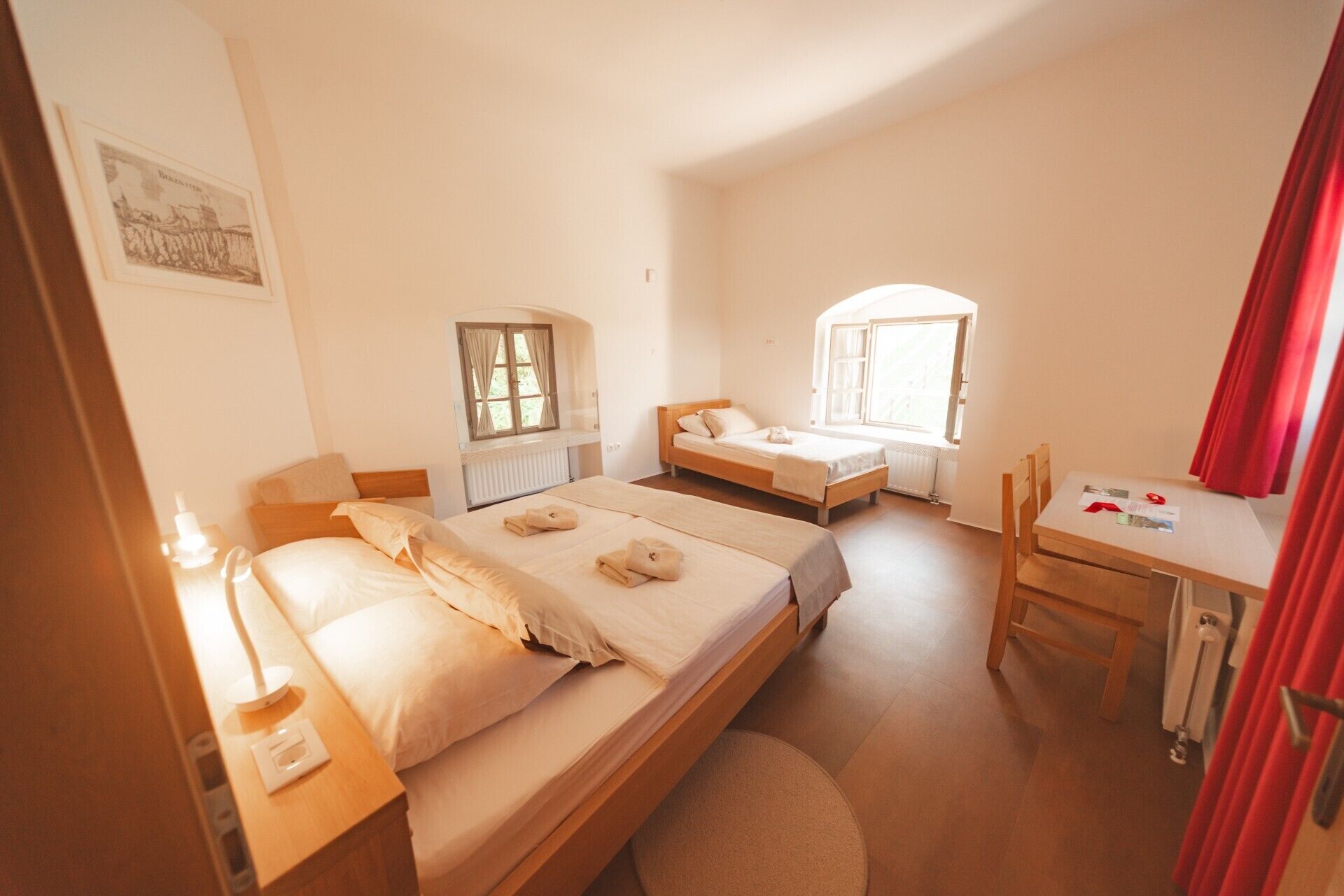 Quarto com duas camas, uma escrivaninha e uma cadeira.