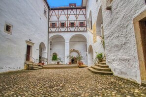 Un patio con suelo de adoquines, paredes blancas y varios arcos.