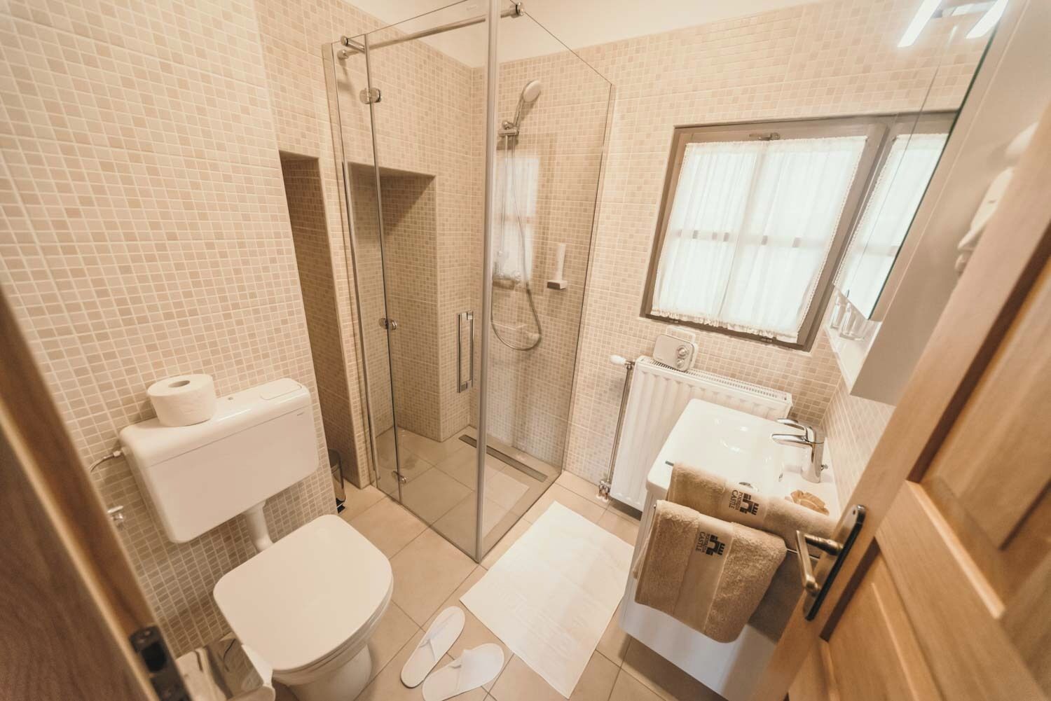Une salle de bain avec une douche à parois de verre, des toilettes, un lavabo et une fenêtre.