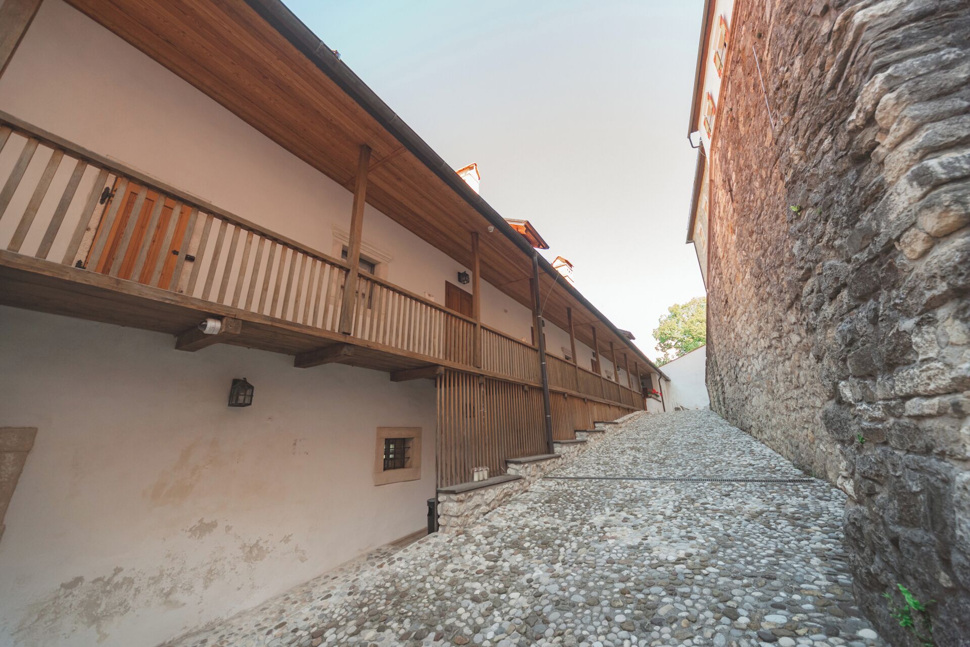 Una calle adoquinada estrecha bordeada por edificios con balcones de madera y muros de piedra.