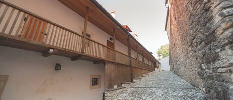 Una calle adoquinada estrecha bordeada por edificios con balcones de madera y muros de piedra.