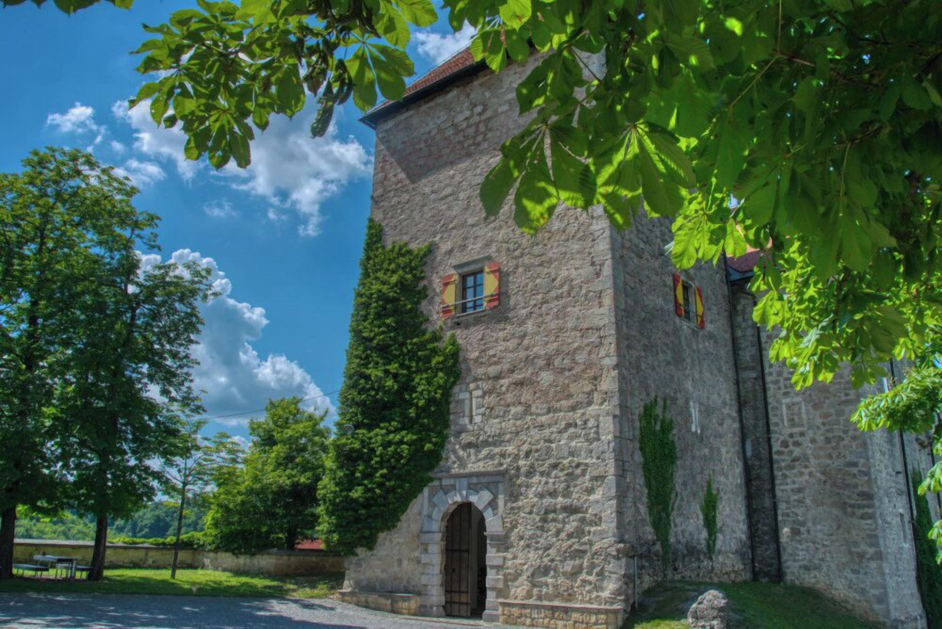 A stone building with a small arched entrance and a window with shutters.