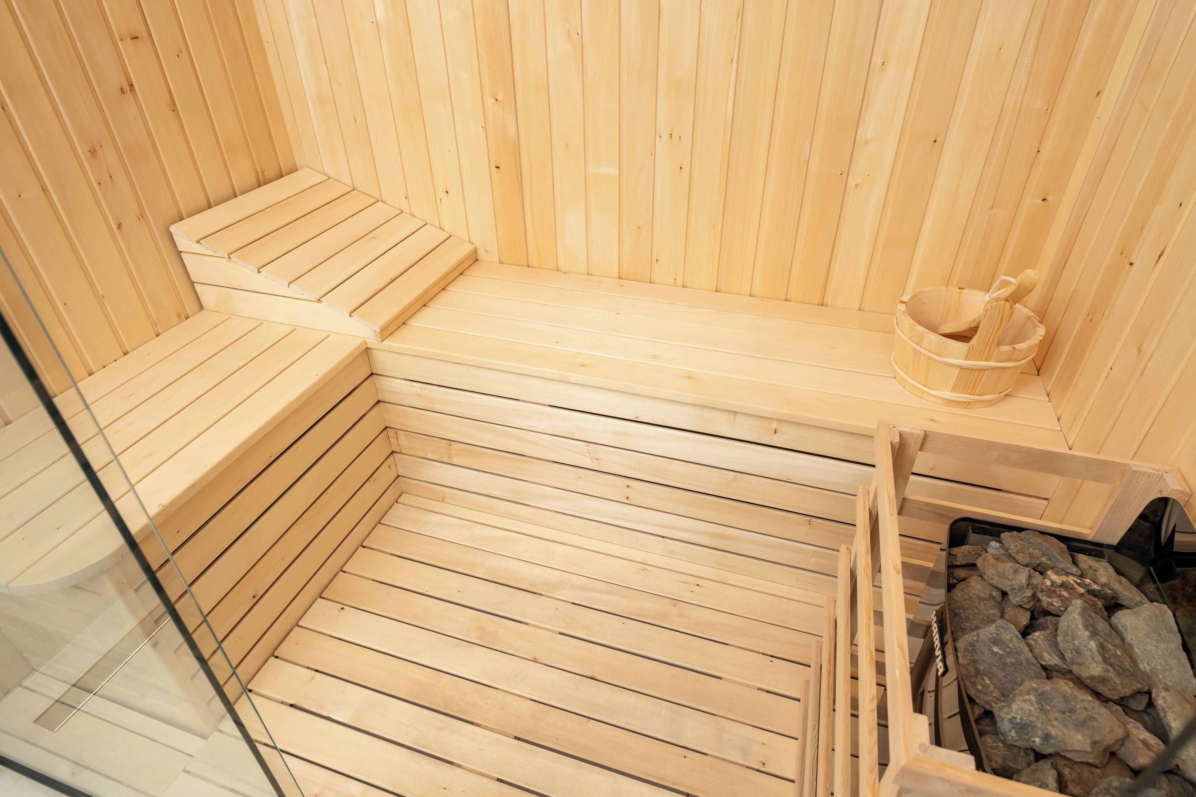 A wooden sauna with benches and a stone-filled container.