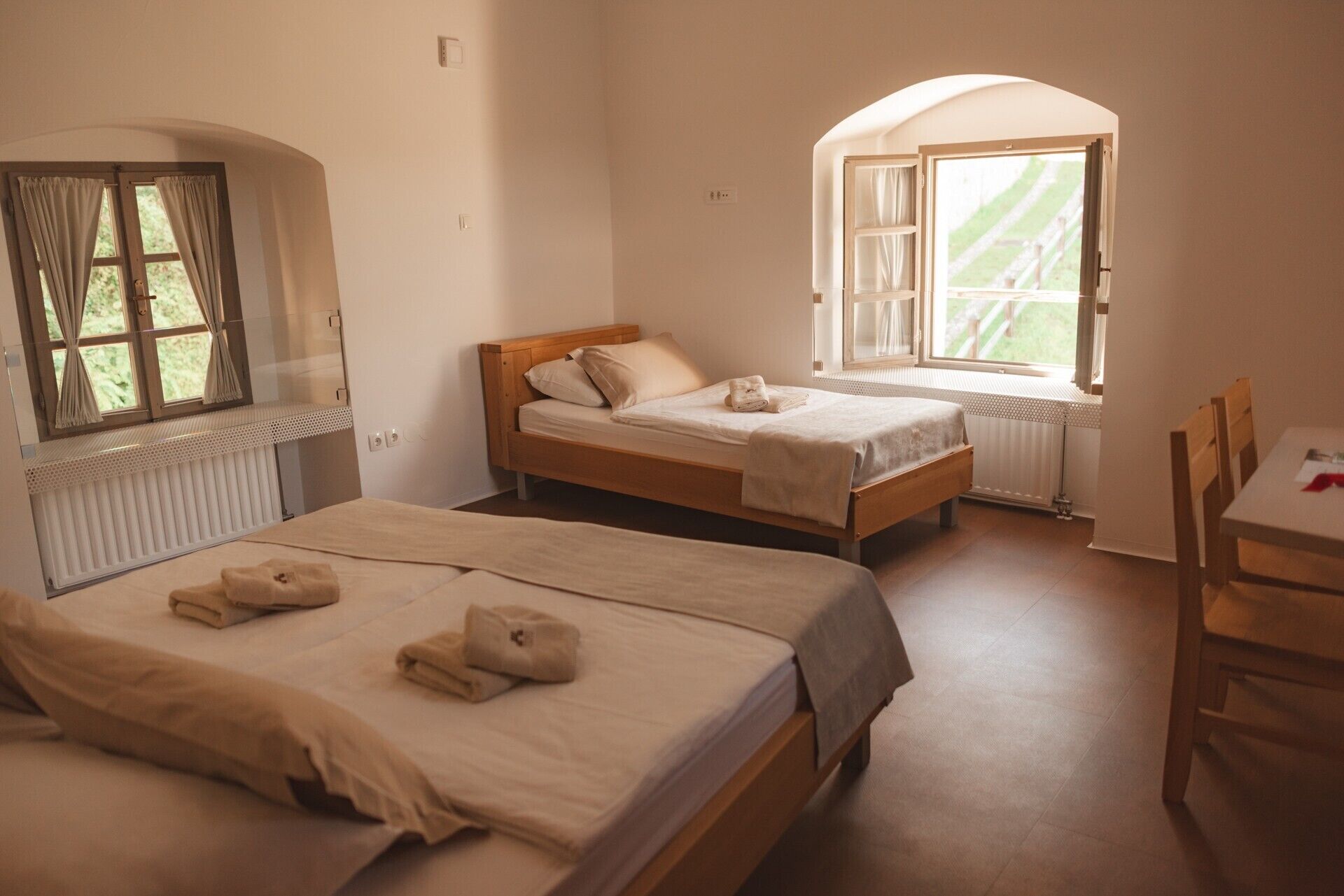 Une chambre avec deux lits, une fenêtre avec des rideaux, un radiateur et une chaise.