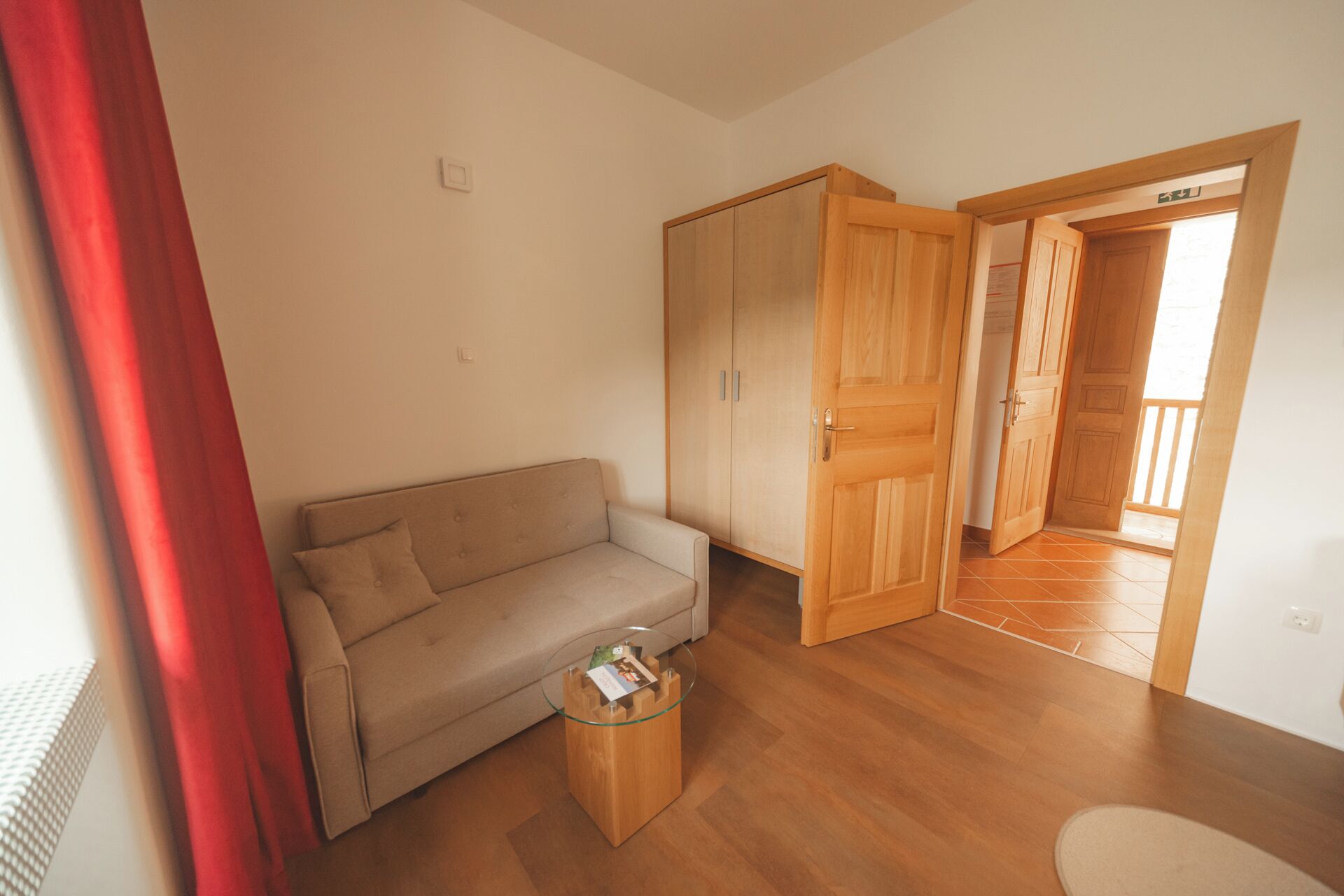 Ein Zimmer mit einer Couch, einem Glastisch, Holzboden und einem Kleiderschrank.