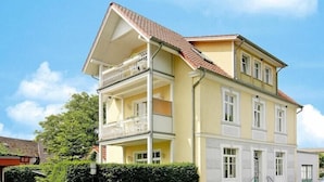A two-story building with a balcony on the upper floor, a small front porch, and a visible entrance.