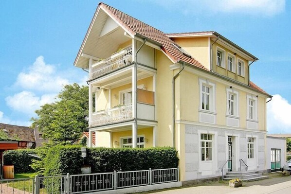 A two-story building with a balcony on the upper floor, a small front porch, and a visible entrance. - Charmante Ferienwohnung auf Rügen, Altenkirchen (Altenkirchen)