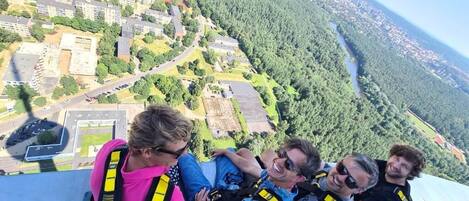 A group of people bungee jumping with a cityscape and forest in the background.